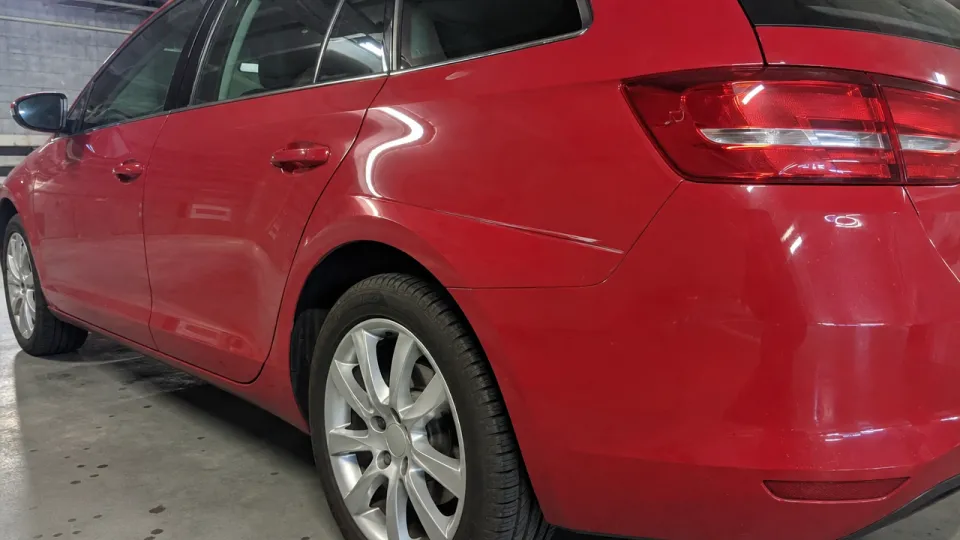 Kırmızı hatchback'in arka çamurluğunda kapı sürtmesinden oluşmuş çizgi biçimli göçük